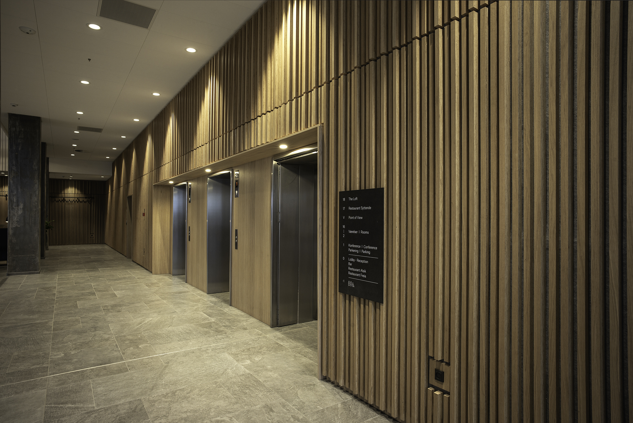 Hotelkorridor med trævæg og elevatorer