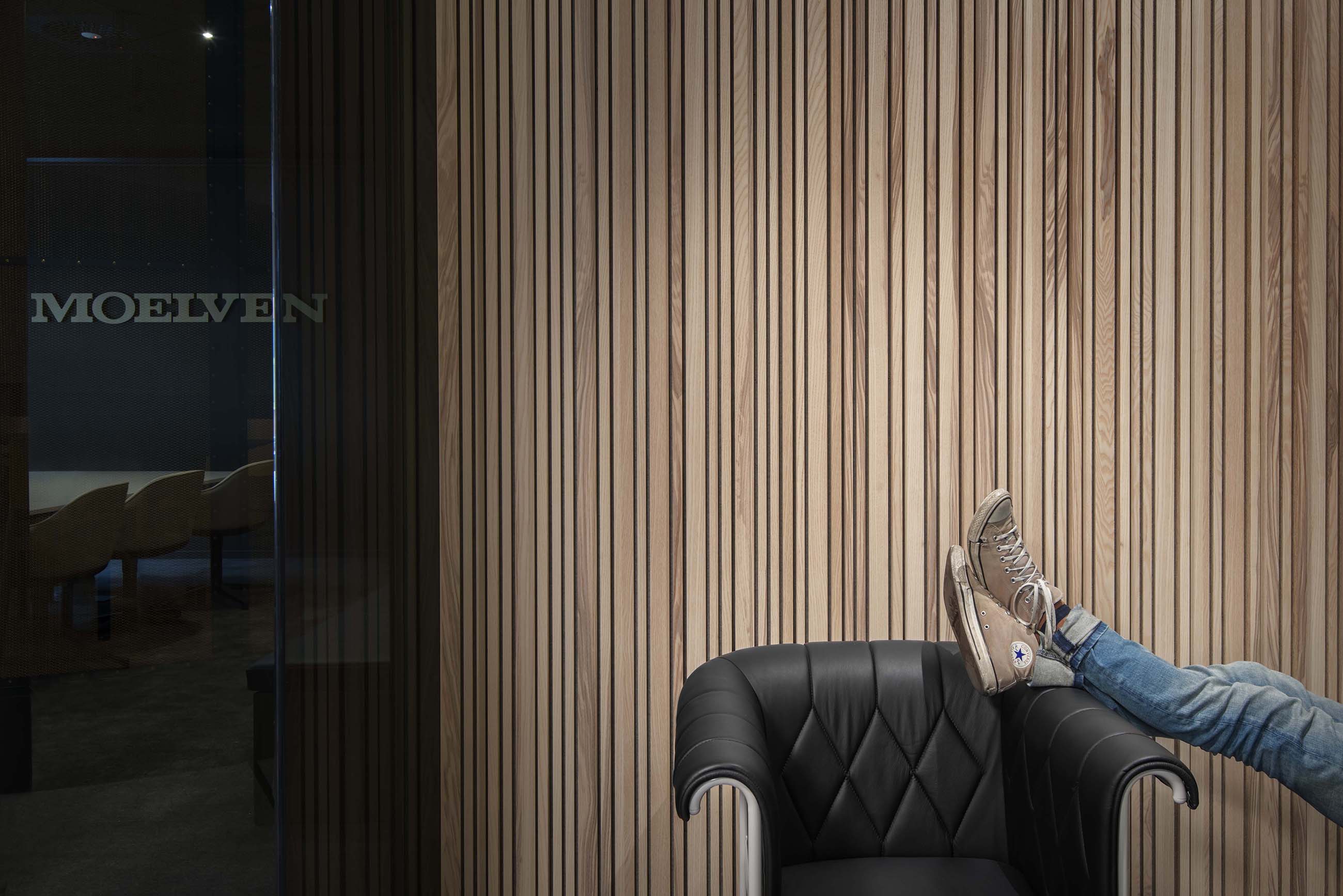 Hvilende ben på sort lænestol foran væg med stripe panel