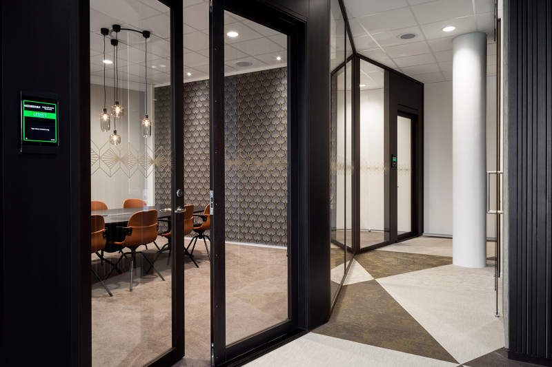 Glasdør ind til mødelokale med mørke træpaneler på væggene