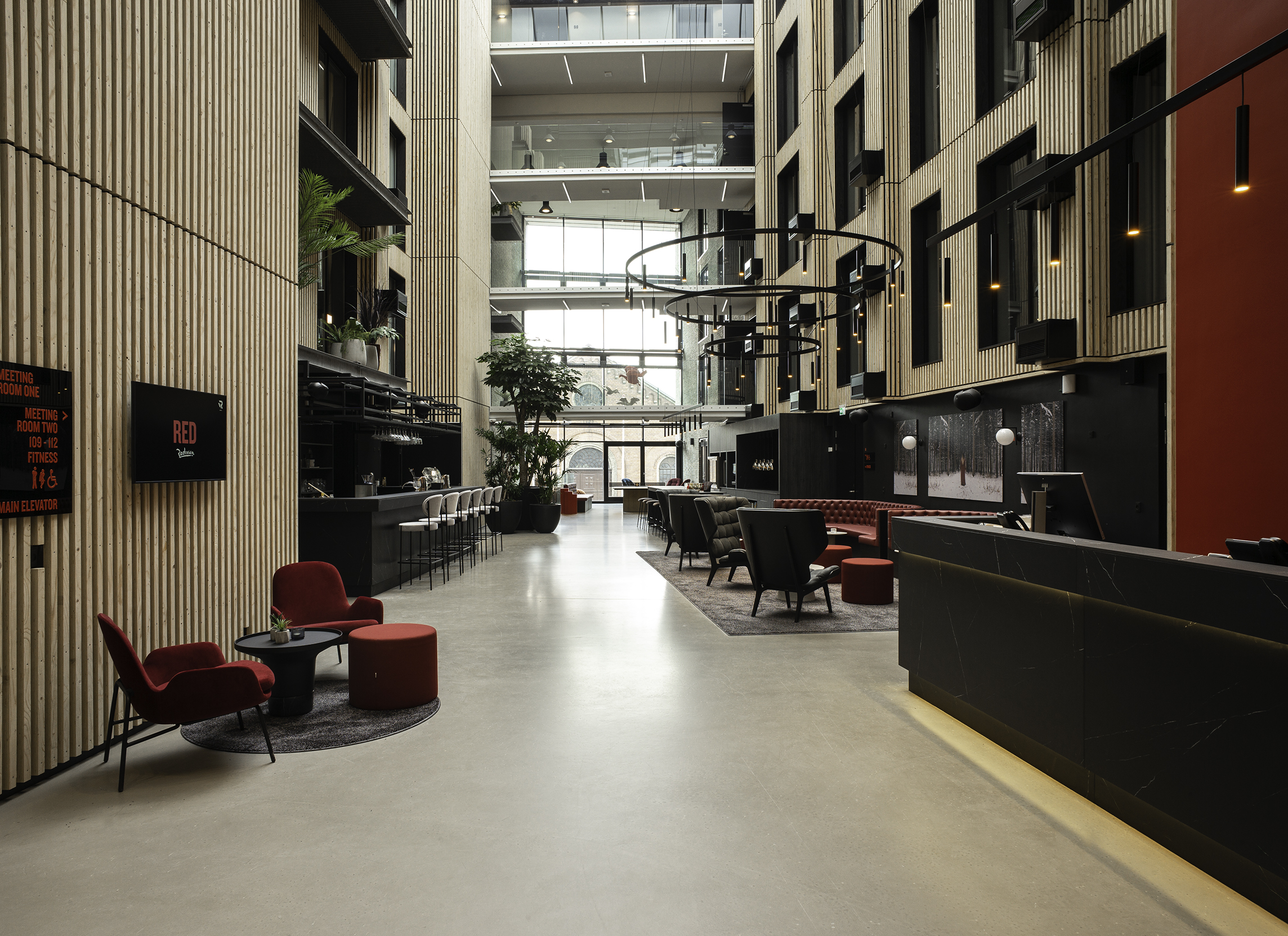 Radisson Red, Aarhus - Reception foran rød væg i atrium med trælameller på vægge